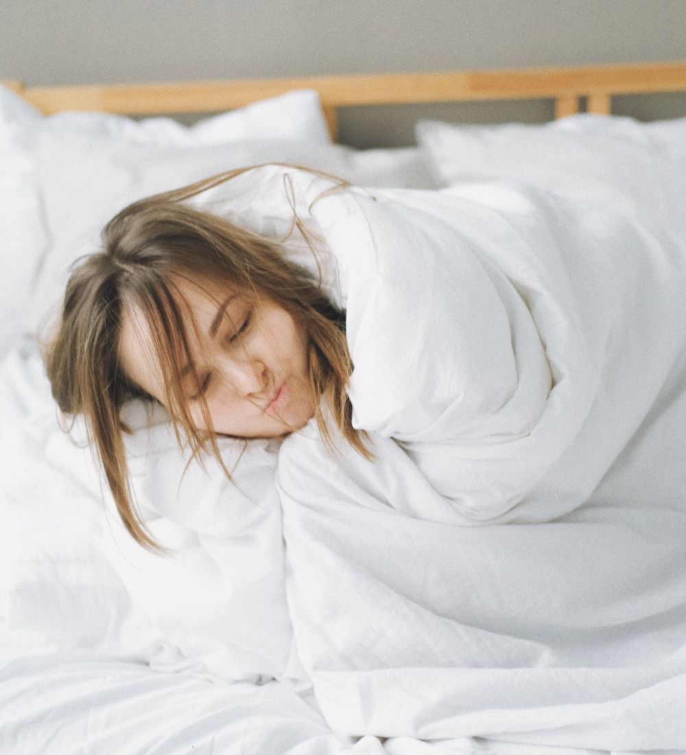 Personne endormie sereinement sous une couette blanche